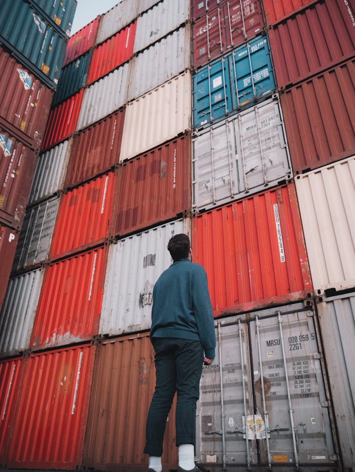 Man in Blue Dress Shirt Looking At A Stack Of Cargo Containers